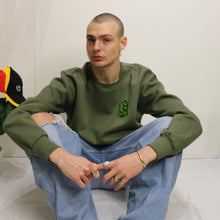 Load image into Gallery viewer, Stylish green embroidered sweatshirt from Manifest x Friends of Montys collection, designed for warmth and fashion.