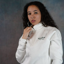 Load image into Gallery viewer, Female model wearing a white Manifest 1/4 zip sweatshirt with embroidered logo, showcasing casual style and comfort.