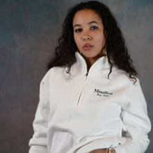 Load image into Gallery viewer, Female model wearing a white 1/4 zip sweatshirt with embroidered Manifest logo, showcasing a stylish and casual look.