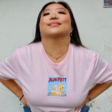 Load image into Gallery viewer, Person wearing a pink t-shirt with a graphic design and text, standing against a plain wall.
